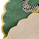 Corner detail of scalloped snake rug showing plush green pile, gold trim and woven underside