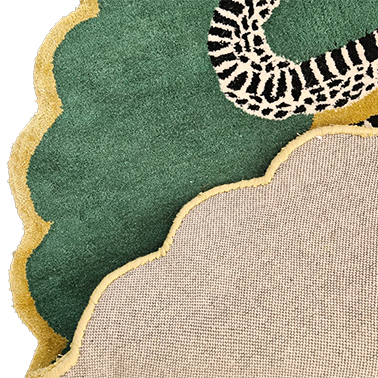 Corner detail of scalloped snake rug showing plush green pile, gold trim and woven underside
