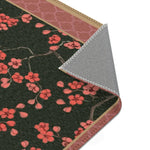 Corner of imperial arch bloom rug folded to reveal grey backing, pink quatrefoil border and blossoms