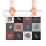 Hands unrolling the Cosmic Balance mat, revealing celestial sun and moon checkerboard tiles