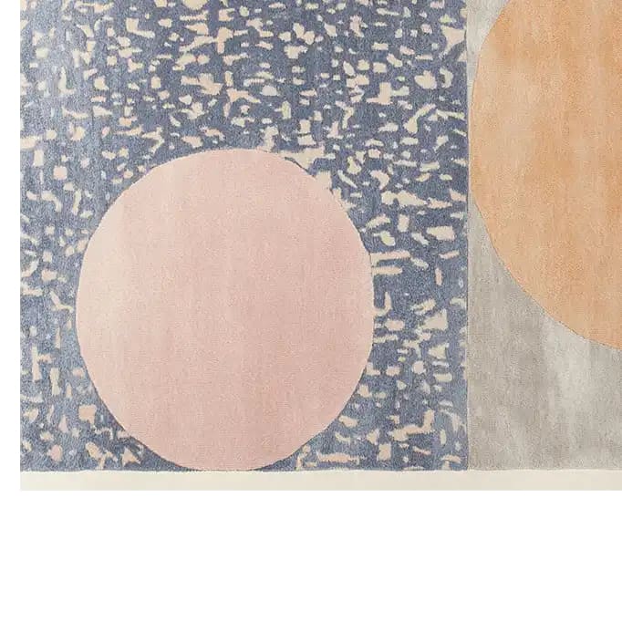 A vibrant area rug featuring a hand-tufted wool design with abstract patterns. The rug showcases large circular shapes in pastel colors against a textured blue and gray background, adding a touch of modern elegance to any room.