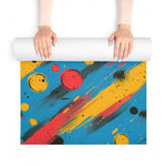 Hands unrolling Cosmic Energy Flow yoga mat with bold red orb and diagonal paint streaks on blue