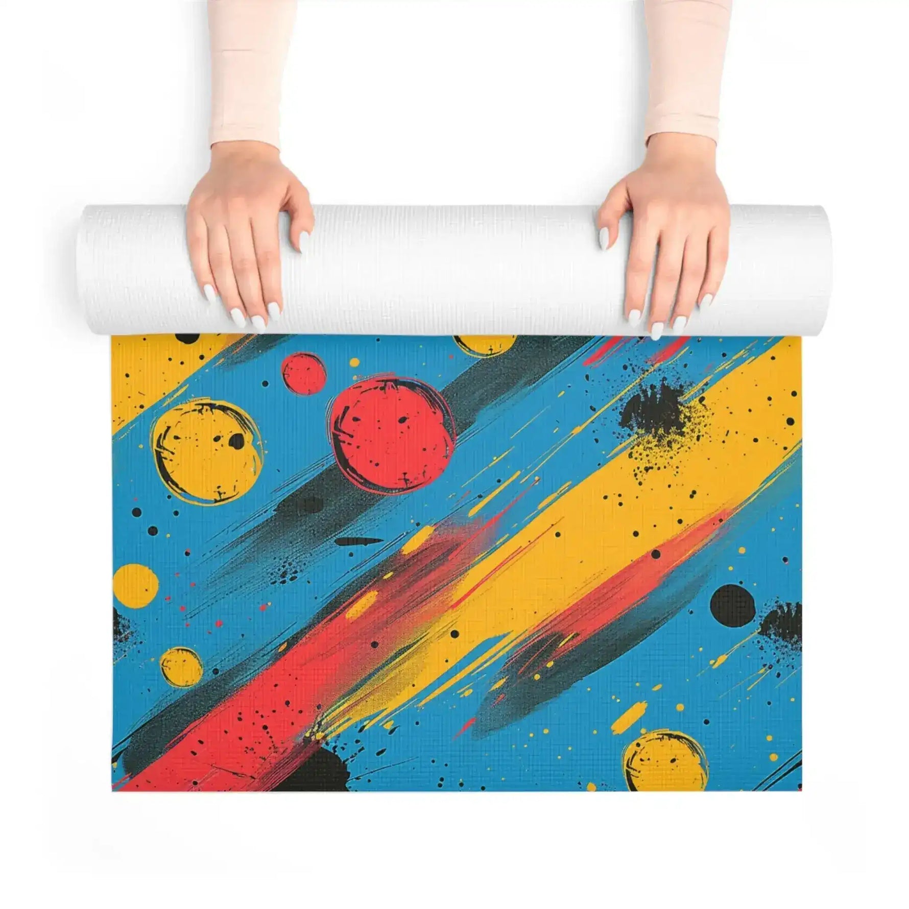 Hands unrolling Cosmic Energy Flow yoga mat with bold red orb and diagonal paint streaks on blue