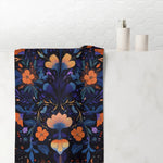 Dark navy bath towel bold orange and purple embroidery floral symmetrical botanical print hanging in bathroom