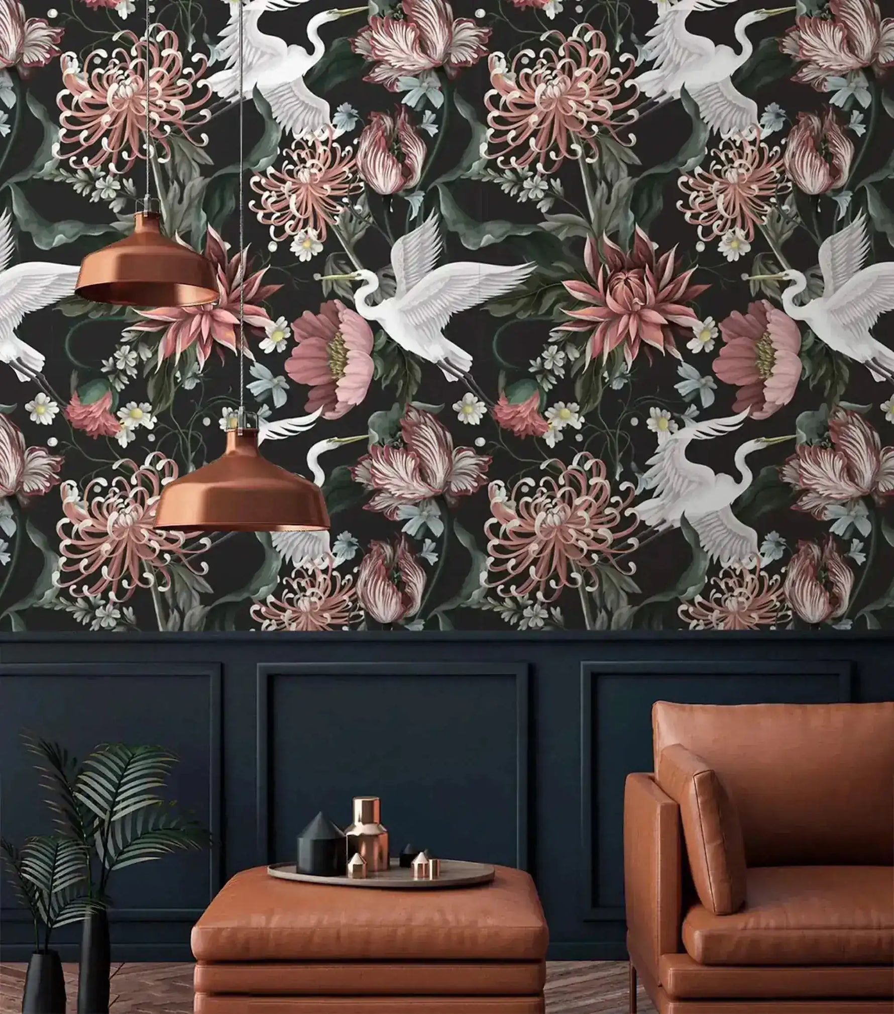 Crane blooms wallpaper on upper wall above navy paneling; copper pendants and brown leather armchair in moody room