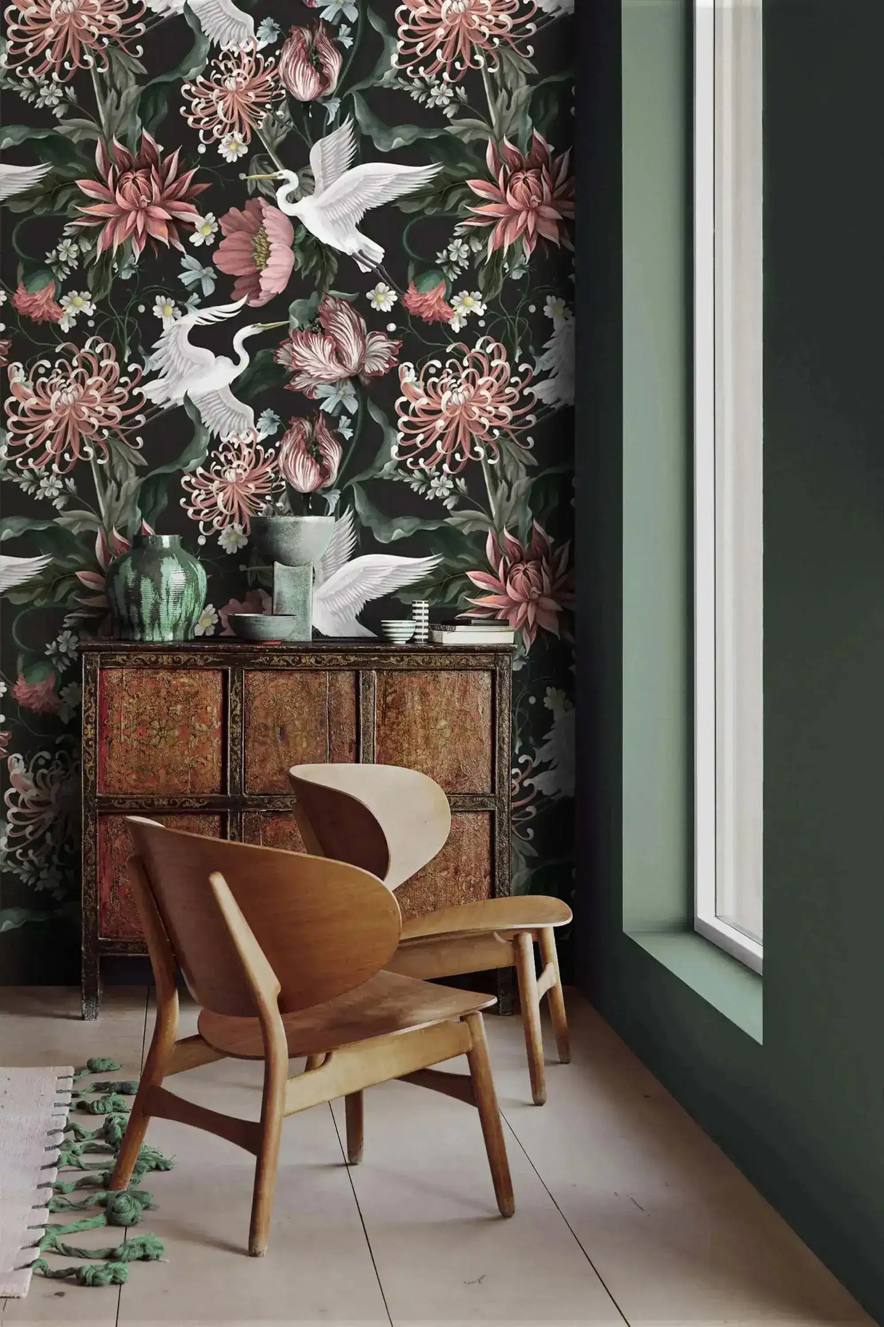 Crane blooms wallpaper with wooden lounge chair and ornate cabinet; sage green accent wall and tall window beside