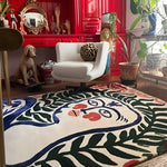 Cream hand-tufted rug with an abstract woman's face framed by green ferns, styled in an eclectic red-walled room