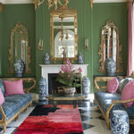Crimson and black abstract wool runner on a checkered floor in a grand green salon with gilt mirrors and blue sofas