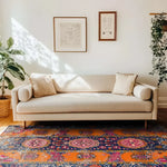 A beautifully styled living room featuring a Crimson Flora Hand Knotted Area Rug. This vintage rug showcases intricate Persian designs with bold colors, making it a standout piece among large living room rugs. The rug perfectly complements the neutral-toned sofa and the framed artwork on the wall, creating an inviting and elegant atmosphere.