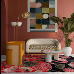 A vibrant living room featuring a Crimson Paradise Hand Tufted Area Rug with an abstract design in red and black hues. The wool rug adds a luxurious touch to the space, complementing the modern furniture and large wall art. Perfect for enhancing any living room area.