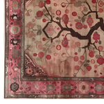 A detailed view of the Crimson Reverie Knotted Wool Rug showcasing intricate floral patterns in shades of red and pink against a beige background. The rich border frames the area rug with ornate designs, creating a captivating centerpiece for any room.