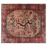 A beautifully designed area rug featuring an intricate floral pattern with branches and red blossoms, surrounded by a decorative border in shades of crimson and pink.