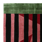 Close-up view of the Crimson Shadow Columns Hand Tufted Rug, showcasing its contemporary design with bold red, black, and green stripes. This wool area rug is perfect for adding a modern touch to any living room.