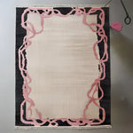 Top view of the Crimson Thread Hand Knotted Wool Rug, showcasing its intricate design with pink abstract patterns on a dark border, ideal for an office or formal dining room setting. This area rug adds a touch of elegance to any dining room or office space.