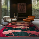 A stylish modern living room featuring a Crimson Valley Hand Tufted Rug. The area rug showcases a vibrant abstract design with rich crimson and deep green hues, perfect for enhancing large living rooms or office spaces. The wool rug complements the sleek leather chairs and large windows, adding warmth and elegance to the area.