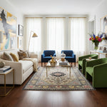 Living room with a white sofa, a traditional wool rug, blue chairs, and green armchair. 