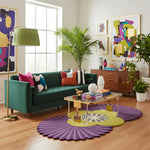 Living room with a green sofa, colorful pillows, and a purple rug.