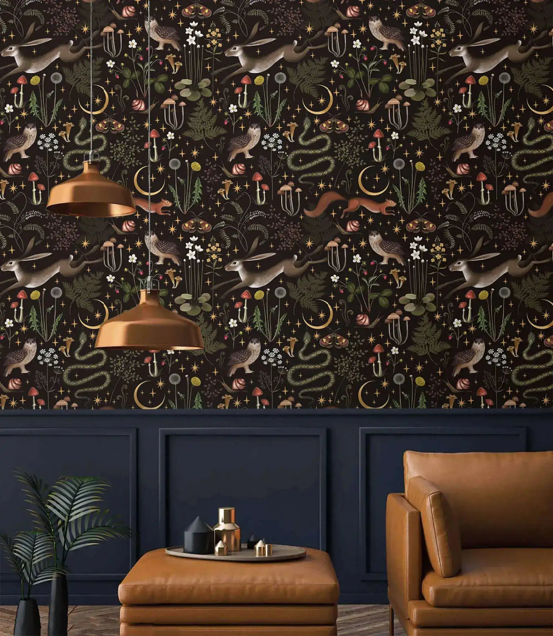 Enchanted Wilderness wallpaper styled in a dark living room with leather chair, copper pendants, navy paneling below