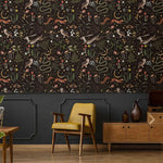 Enchanted Wilderness wallpaper above dark grey paneling; retro yellow armchair and oak sideboard in moody sitting room