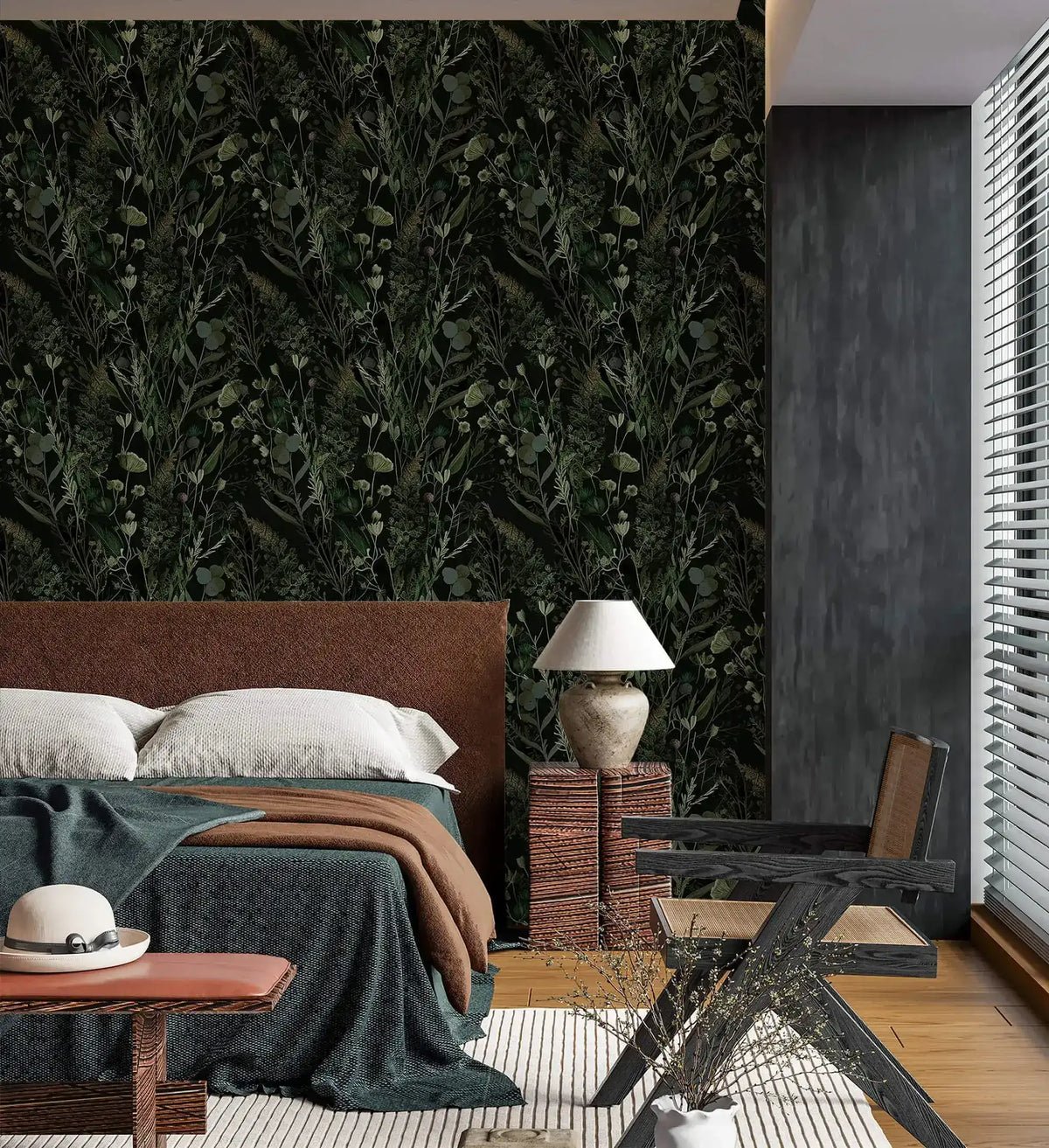Dark green botanical fern and floral wallpaper in moody bedroom with leather bed, lamp and woven nightstand