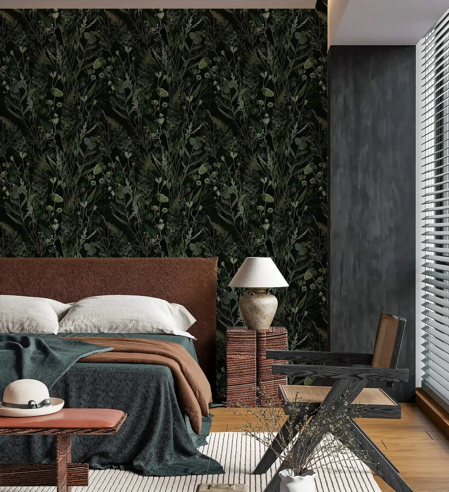 Dark green botanical fern and floral wallpaper in moody bedroom with leather bed, lamp and woven nightstand
