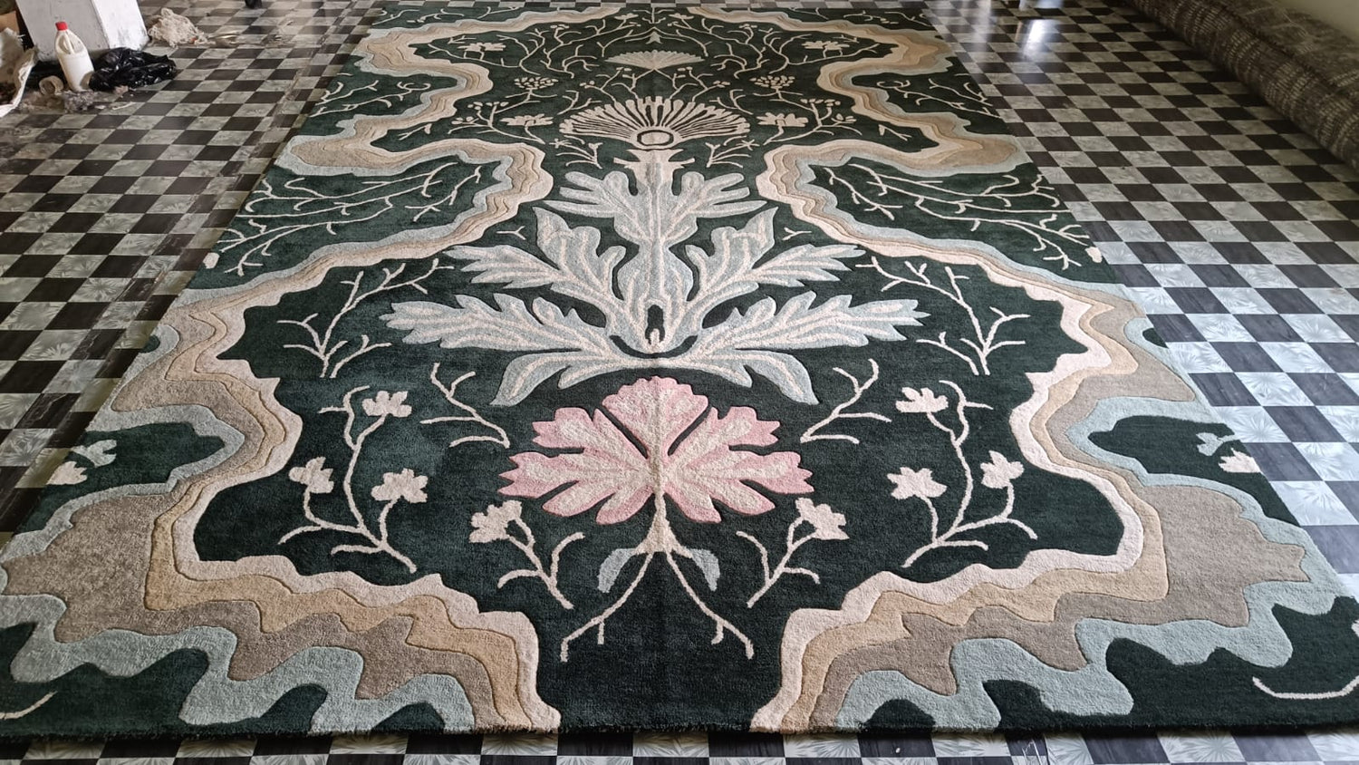 Dark green botanical rug with pink bloom and plush pile shown on a checkered tile floor