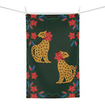 Dark green kitchen towel hung on a line, featuring two seated golden leopards and a red floral border
