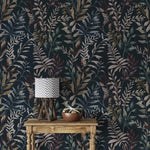 Dark navy botanical wallpaper covering full wall behind wooden console table with chevron table lamp and copper bowl.