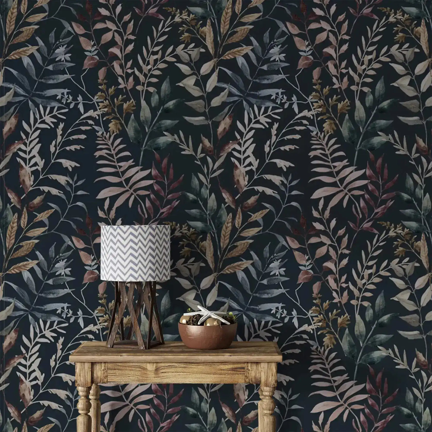 Dark navy botanical wallpaper covering full wall behind wooden console table with chevron table lamp and copper bowl.