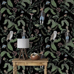 Dark woodland wallpaper detailing owls, a dapper stag and hares with mushrooms and berries on black behind a wood table