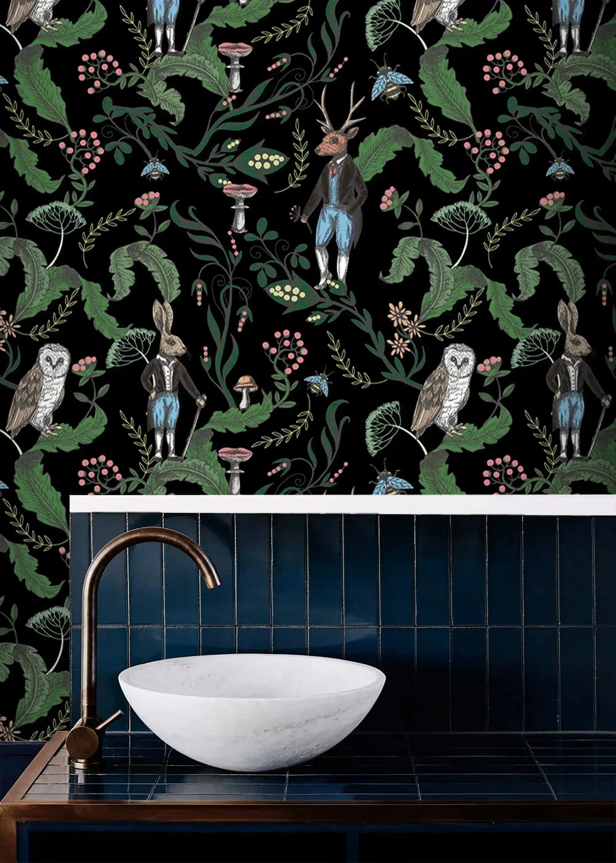 Dark woodland wallpaper with owls, a stag and hares on black above a blue-tiled vanity with a stone basin