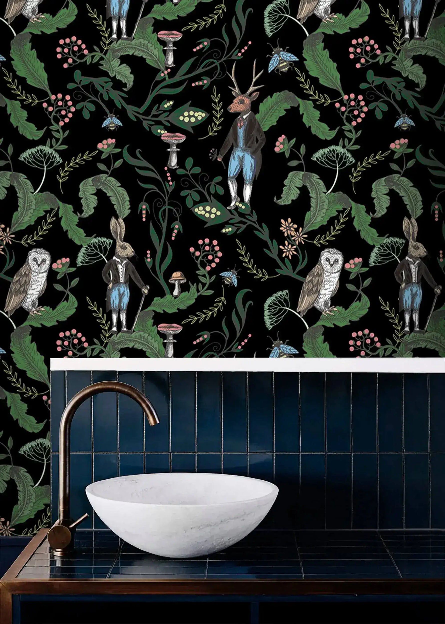 Dark woodland wallpaper with owls, a stag and hares on black above a blue-tiled vanity with a stone basin