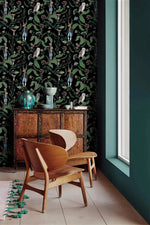 Dark woodland wallpaper with owls and hares on black beside a teal wall and carved wood cabinet