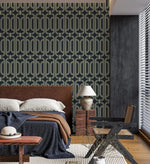 Deco geometric wallpaper with gold linked-oval lines on navy as a bedroom feature wall behind an upholstered bed