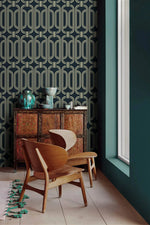 Deco geometric wallpaper with gold linked-oval lines on navy beside a teal wall and carved wood cabinet