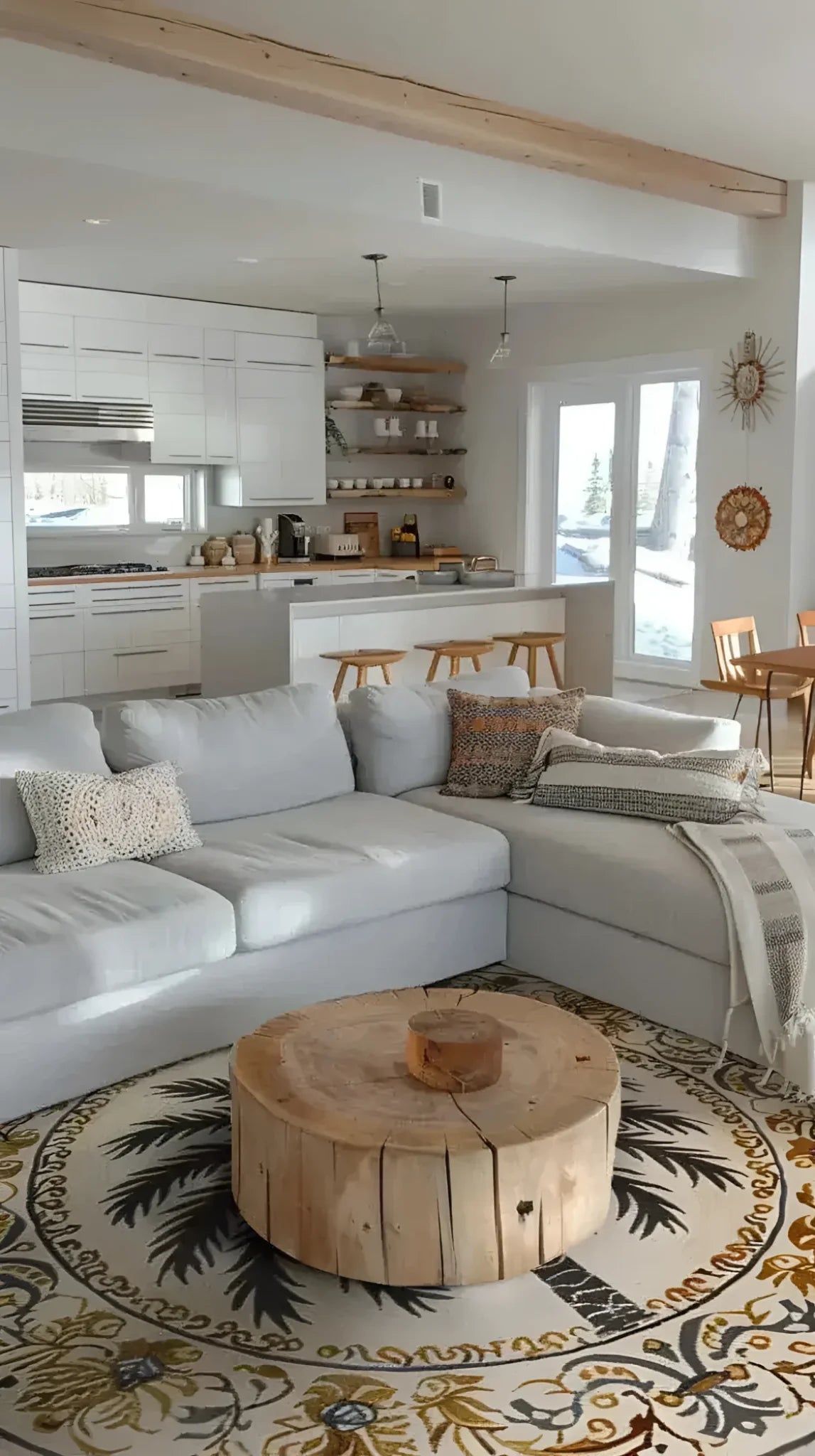 A cozy living room featuring a Desert Paradise Hand Tufted Round Rug. This large area rug, ideal for a living room, showcases intricate patterns and rich colors that complement the neutral tones of the surrounding furniture. The wool rug is paired with a rustic wooden coffee table, enhancing the warm and inviting ambiance of the space.