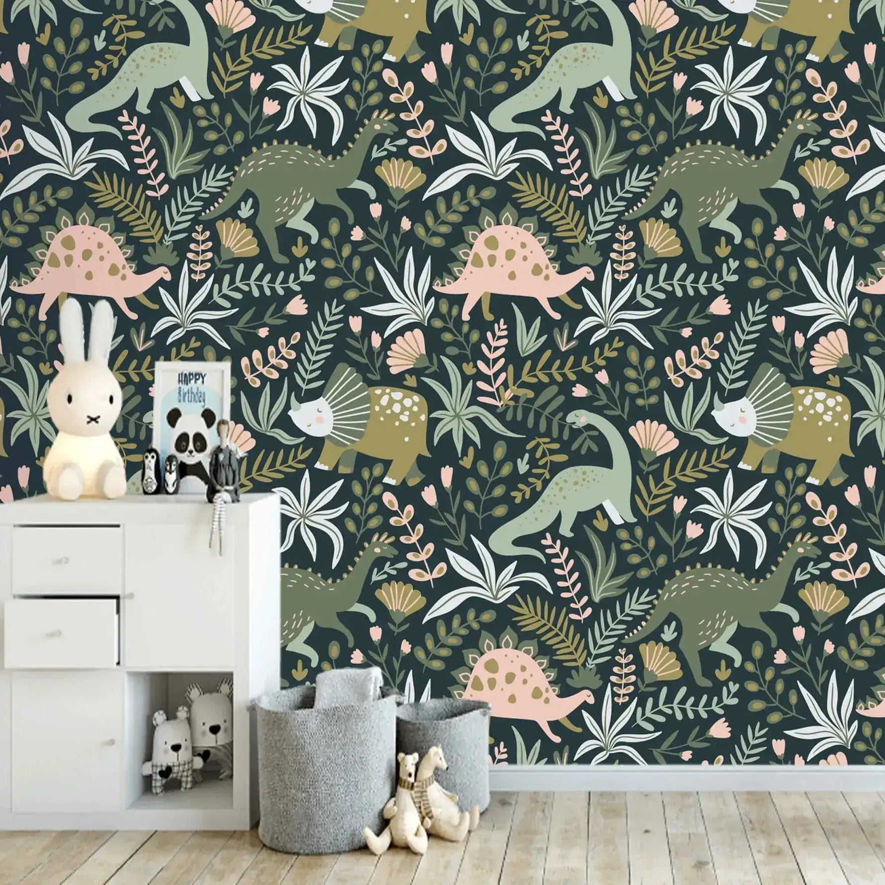 Dino Garden Oasis wallpaper in kids room with white chest of drawers, bunny lamp, gray felt storage baskets, and stuffed toys.