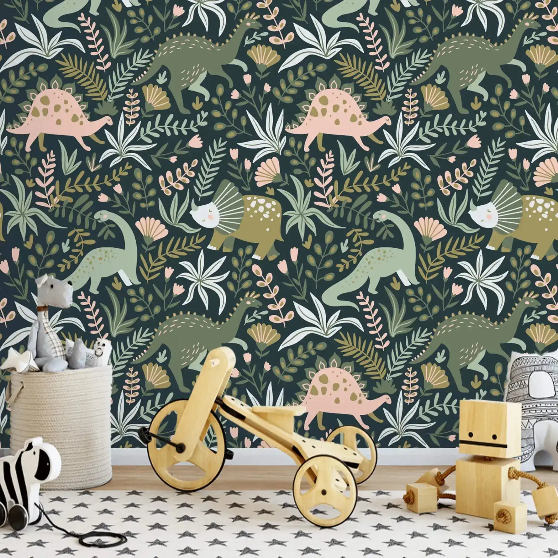 Dino Garden Oasis wallpaper with green and pink dinosaurs on navy in playroom with wooden balance bike and toy blocks.