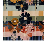 A vibrant, hand-tufted wool area rug featuring a bold floral design with abstract daisies in various colors including navy, pink, orange, and yellow against a striped background.