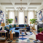 Modern living room with blue sectional sofa, colorful rug, and abstract art.