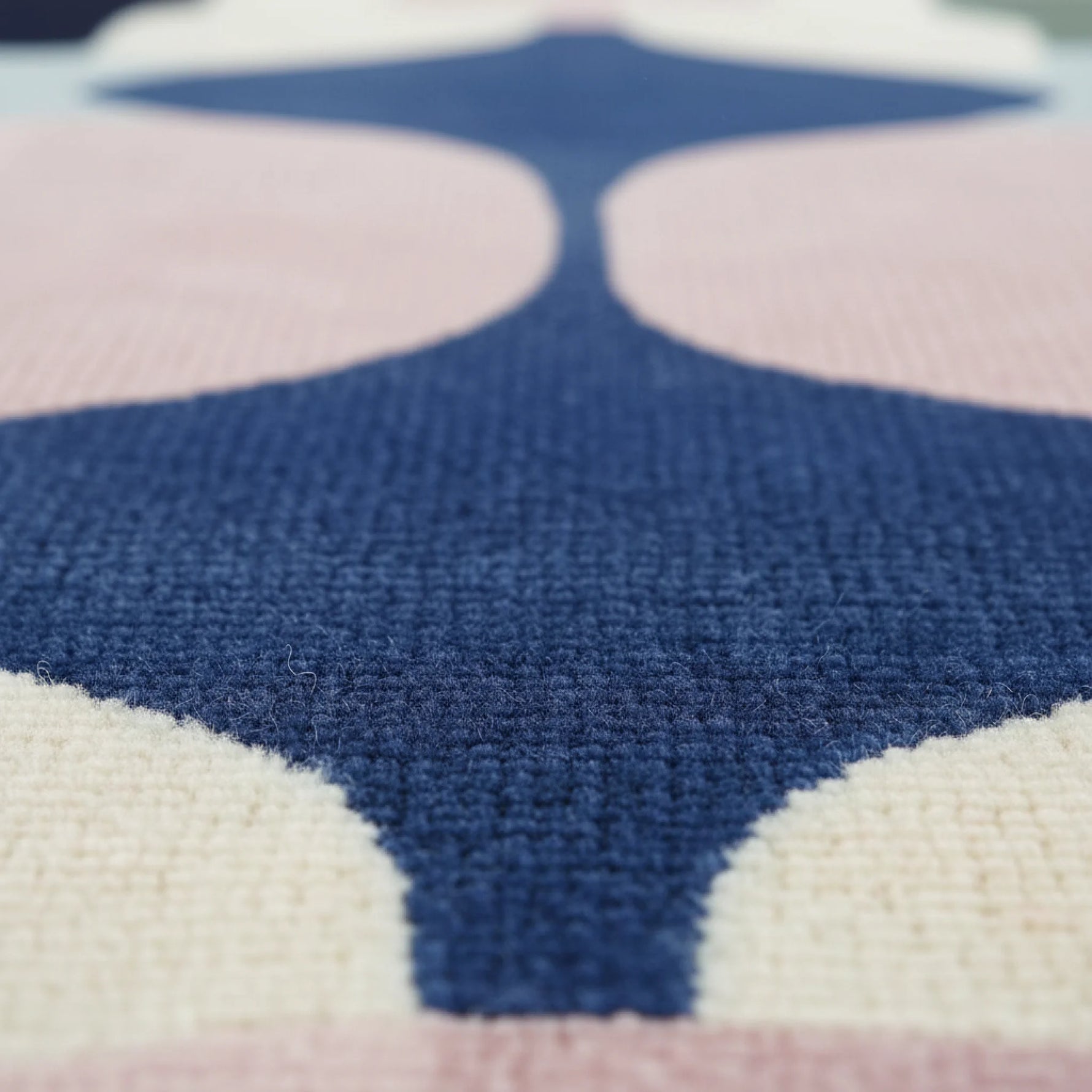 Close-up of a patterned tufted wool rug with blue, pink, and white colors.