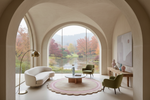 A luxury modern living room with a large arched window overlooking a scenic autumn lake landscape. The room features a white curved sofa, two olive green armchairs, a round pink and beige rug, a wooden coffee table, and a tall floor lamp, all framed by beige stone arches.