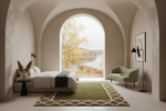 A modern bedroom interior with a large arched window overlooking a lake and autumn trees. The room features a low bed with white bedding, a green patterned rug, a green armchair, and textured beige walls.