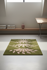 An olive green area rug with a light pink geometric sunburst pattern, displayed on a light gray floor in a minimalist room setting.
