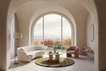 A modern living room with a curved white sofa, a pink armchair, a round coffee table, and a patterned rug in front of a large arched window overlooking a landscape.
