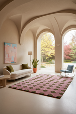 A pink and olive green patterned area rug in a modern, elegant living room with arched windows and a cream-colored sofa.