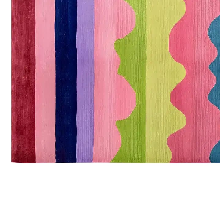Vibrant area rug featuring bold, wavy stripes in various colors including red, blue, purple, pink, green and teal, hand-tufted for a luxurious texture.