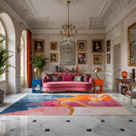 Luxurious living room with a pink sofa, colorful rug, and ornate decor.
