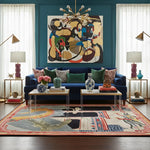 Living room with a blue sofa, colorful rug, and abstract painting on a teal wall.