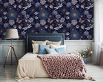Dragonfly Ballet in Blossoms wallpaper on navy bedroom wall; blue upholstered headboard, chunky pink throw, tripod lamp